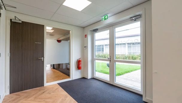 Entreehal met glazen buitendeuren en toegang tot de kantine